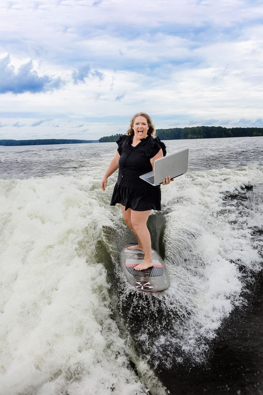 Anna Powell surfing a boat wake with a laptop in hand